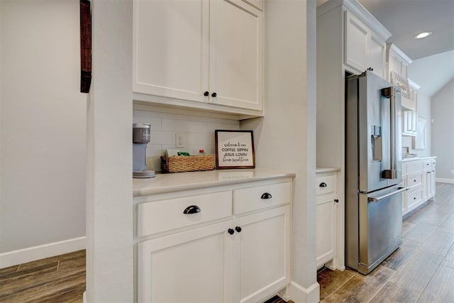 kitchen featuring white cabinets, stainless steel fridge with ice dispenser, tasteful backsplash, and hardwood / wood-style floors