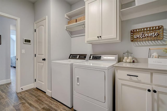 clothes washing area featuring dark hardwood / wood-style floors, cabinets, and washing machine and clothes dryer