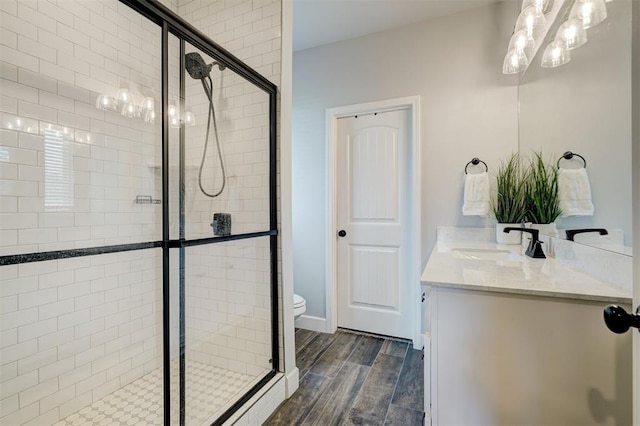 bathroom with wood-type flooring, vanity, toilet, and a shower with door