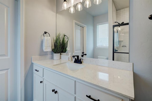 bathroom with walk in shower, vanity, and toilet