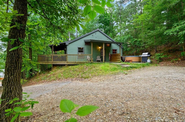 bungalow-style home with a deck and a hot tub