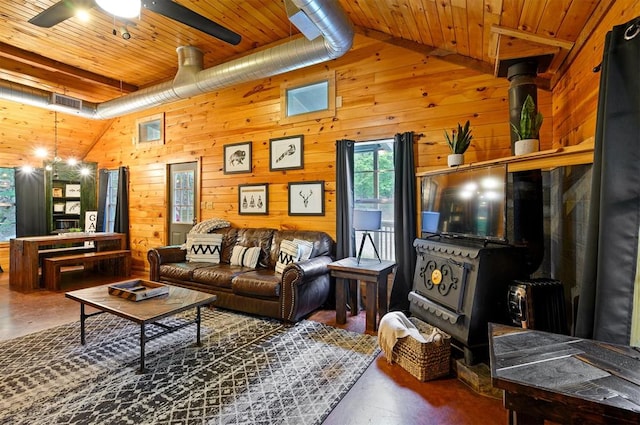 living room featuring wooden ceiling, a wood stove, high vaulted ceiling, wooden walls, and concrete floors