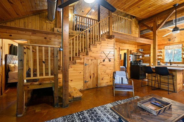 interior space with high vaulted ceiling, ceiling fan, wood ceiling, and wooden walls