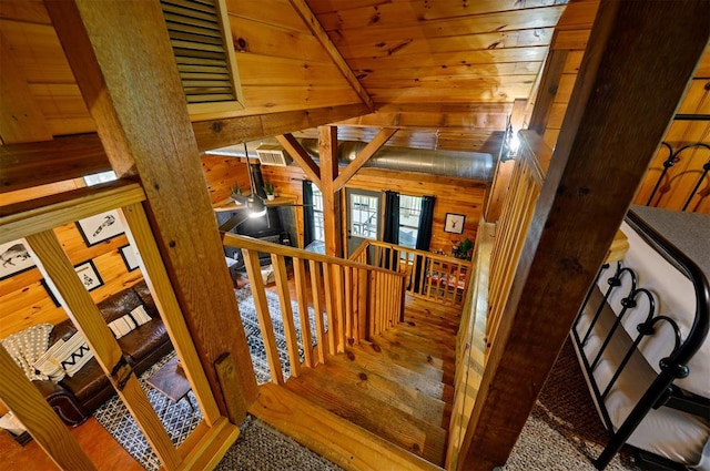 staircase with wooden walls, ceiling fan, lofted ceiling with beams, and wooden ceiling