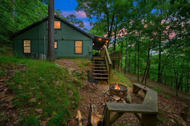 back house at dusk featuring a deck and an outdoor fire pit