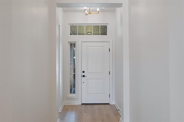 doorway to outside with a chandelier, light hardwood / wood-style flooring, and plenty of natural light