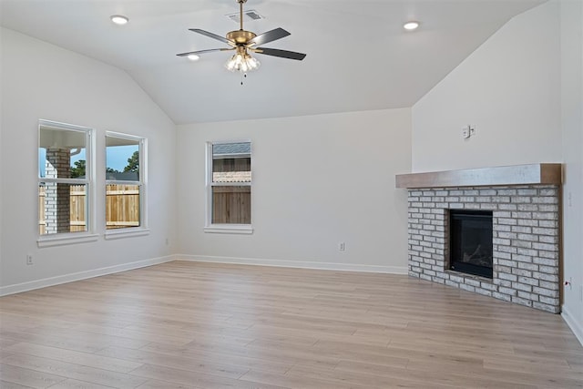 unfurnished living room featuring ceiling fan, lofted ceiling, a fireplace, and light hardwood / wood-style flooring