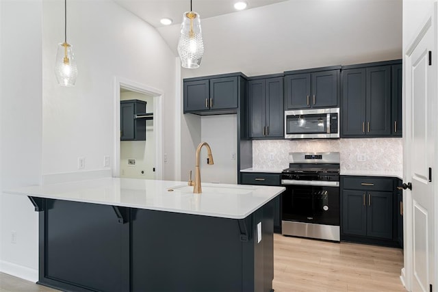 kitchen featuring kitchen peninsula, light wood-type flooring, stainless steel appliances, and hanging light fixtures