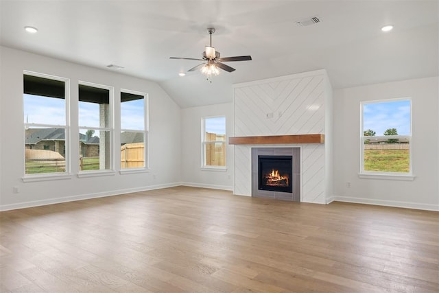 unfurnished living room with ceiling fan, a fireplace, lofted ceiling, and light hardwood / wood-style flooring