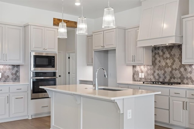 kitchen with a center island with sink, custom exhaust hood, and appliances with stainless steel finishes