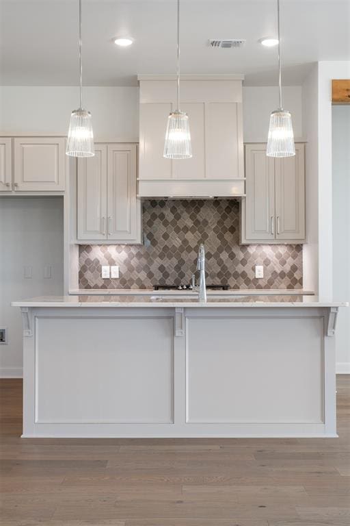 kitchen with light wood-type flooring, hanging light fixtures, and tasteful backsplash