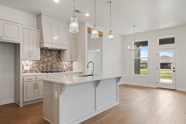 kitchen featuring a center island with sink, pendant lighting, sink, and light hardwood / wood-style flooring