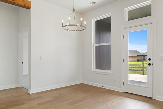 unfurnished dining area with light wood-type flooring and a notable chandelier