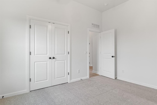 unfurnished bedroom with light carpet and a closet