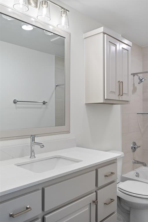 full bathroom with vanity, tiled shower / bath combo, and toilet