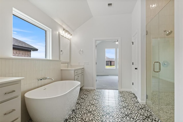 bathroom featuring independent shower and bath, tile patterned floors, vaulted ceiling, and a healthy amount of sunlight