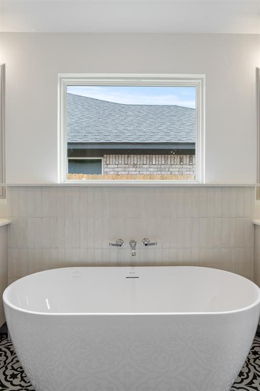 bathroom with a bathtub, vanity, and tile walls