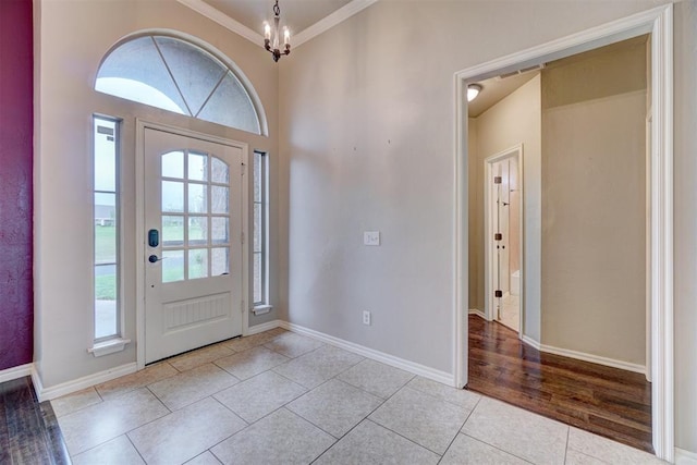 foyer entrance featuring light tile patterned floors, ornamental molding, and a notable chandelier