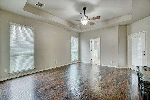 empty room featuring dark hardwood / wood-style floors, ceiling fan, and a tray ceiling