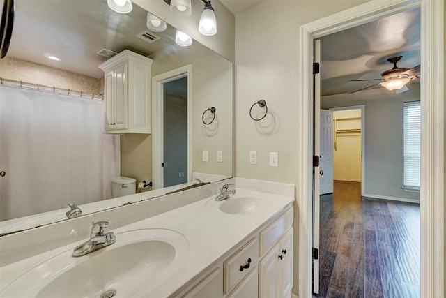 bathroom with ceiling fan, toilet, wood-type flooring, and vanity