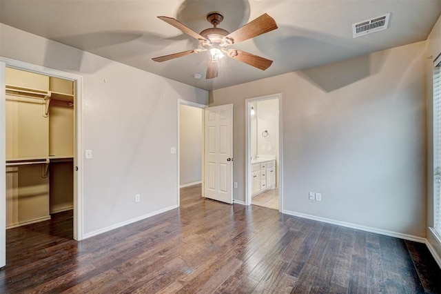 unfurnished bedroom featuring ceiling fan, dark hardwood / wood-style floors, a spacious closet, connected bathroom, and a closet