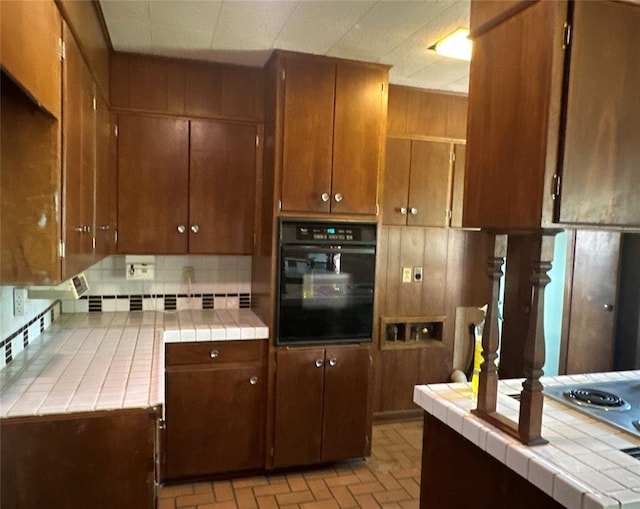 kitchen featuring tile countertops, oven, and decorative backsplash