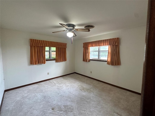 carpeted spare room featuring plenty of natural light and ceiling fan