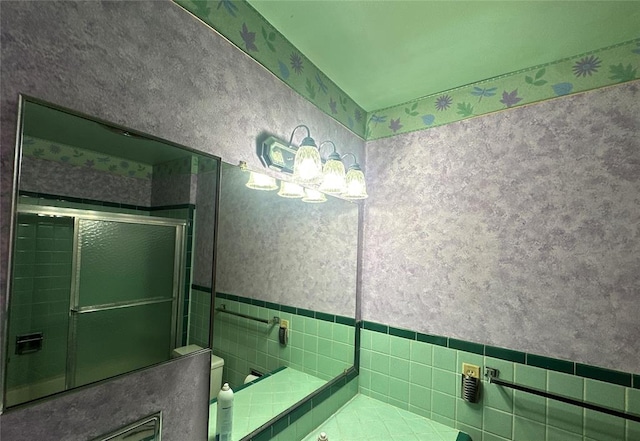 bathroom featuring a shower with shower door, tile walls, and toilet