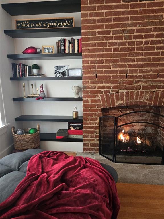 bedroom featuring hardwood / wood-style floors and a brick fireplace