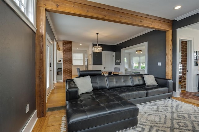 living room featuring light wood-type flooring, an inviting chandelier, and ornamental molding