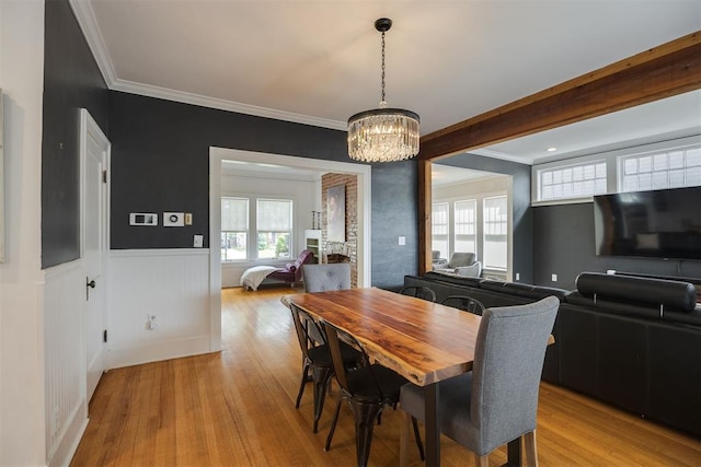 dining space with an inviting chandelier, ornamental molding, and light hardwood / wood-style flooring