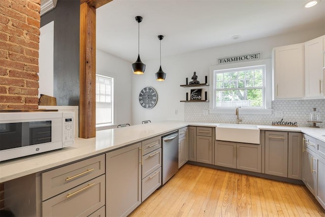 kitchen featuring gray cabinetry, sink, light hardwood / wood-style flooring, stainless steel dishwasher, and pendant lighting