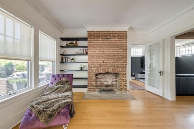 living room featuring light hardwood / wood-style floors, a brick fireplace, a wealth of natural light, and crown molding