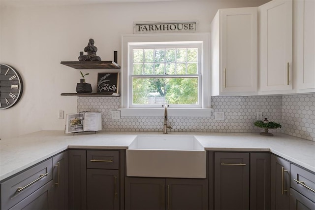 kitchen featuring tasteful backsplash, white cabinetry, and sink