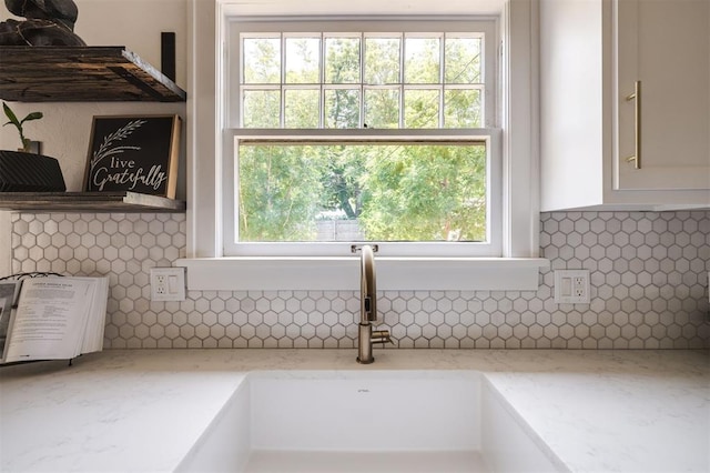 room details with decorative backsplash, light stone countertops, and sink