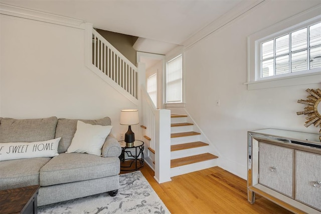 staircase with hardwood / wood-style floors, ornamental molding, and a healthy amount of sunlight