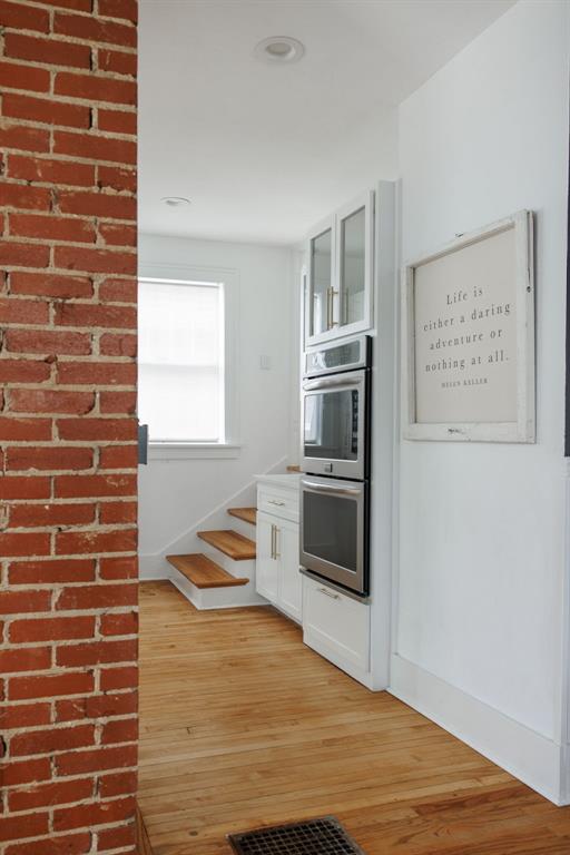 kitchen with double oven, white cabinets, and light hardwood / wood-style floors