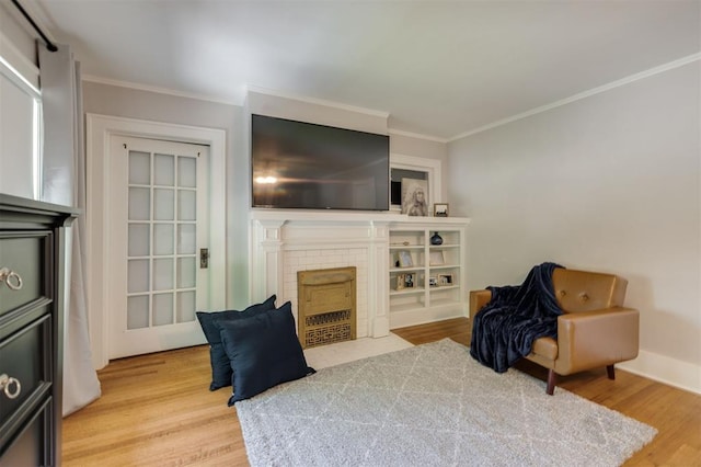 sitting room featuring hardwood / wood-style floors, ornamental molding, and a brick fireplace