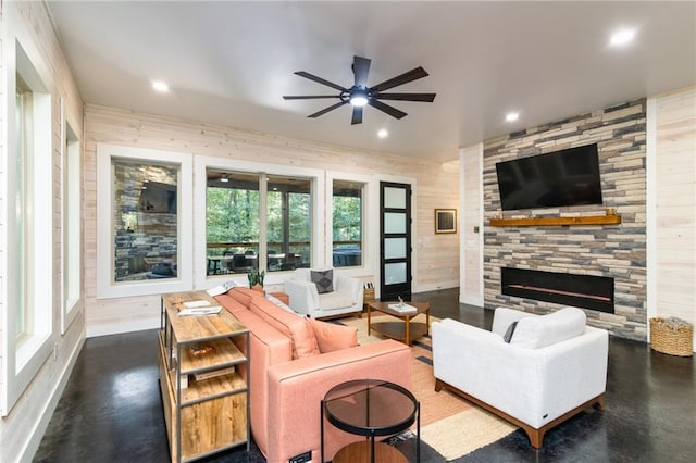 living room featuring a fireplace, ceiling fan, and wood walls