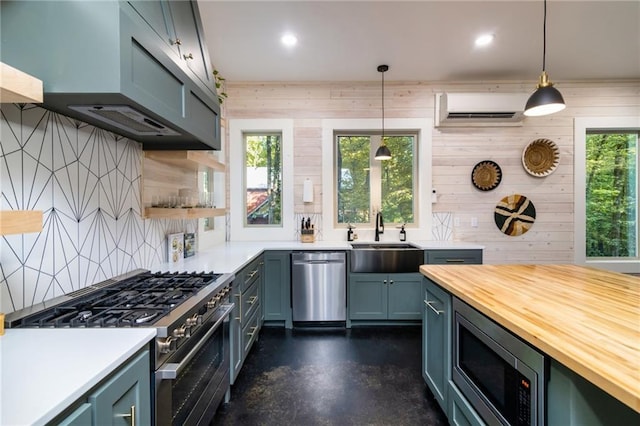 kitchen featuring appliances with stainless steel finishes, tasteful backsplash, pendant lighting, a wall mounted air conditioner, and sink