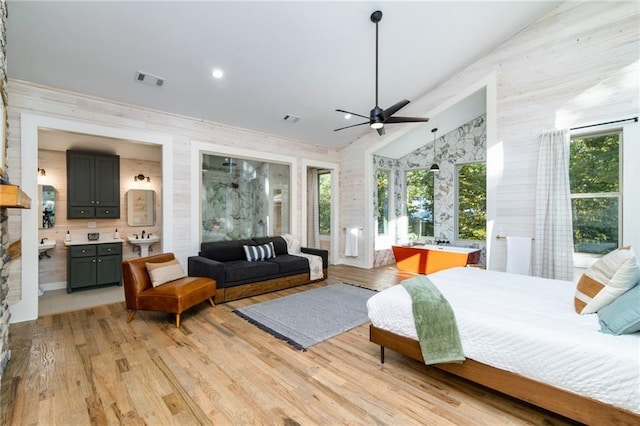 bedroom featuring ceiling fan, light hardwood / wood-style flooring, vaulted ceiling, and ensuite bathroom