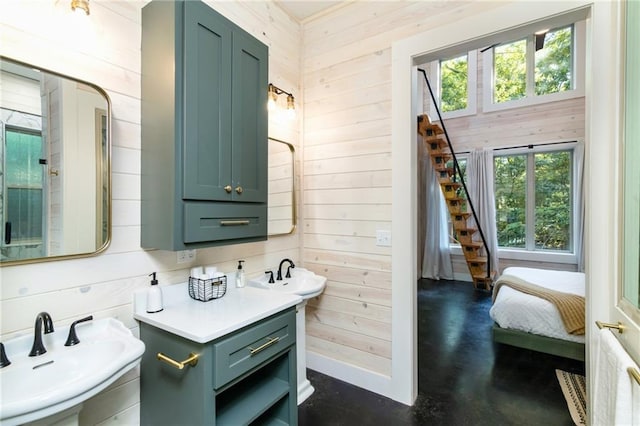 bathroom with double sink, wooden walls, and concrete floors