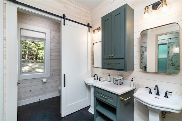 bathroom with dual sinks, wooden walls, and toilet