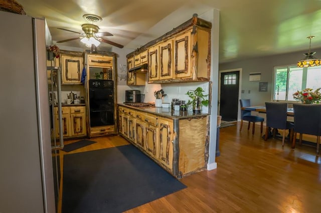 kitchen featuring black double oven, ceiling fan, wood-type flooring, decorative light fixtures, and stainless steel gas stovetop