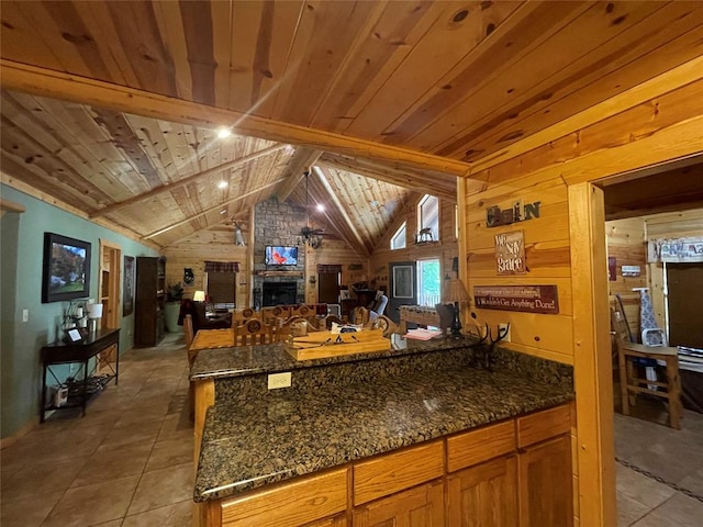 kitchen with wooden walls, a stone fireplace, lofted ceiling, and wood ceiling