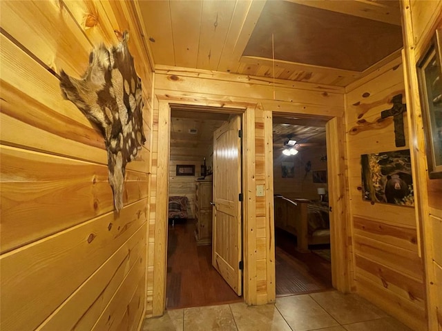 corridor featuring wood walls, light tile patterned floors, and wood ceiling