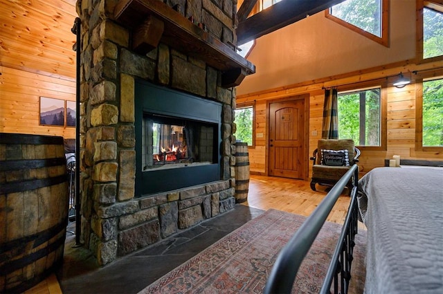 bedroom with wood walls, a towering ceiling, light hardwood / wood-style flooring, and multiple windows