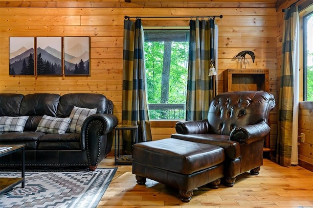 living area with wood walls, light hardwood / wood-style flooring, and plenty of natural light