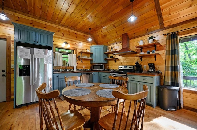 dining room featuring wood walls, plenty of natural light, light hardwood / wood-style floors, and lofted ceiling