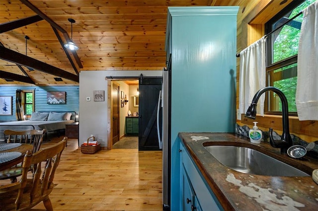 kitchen featuring lofted ceiling with beams, a barn door, a healthy amount of sunlight, and sink